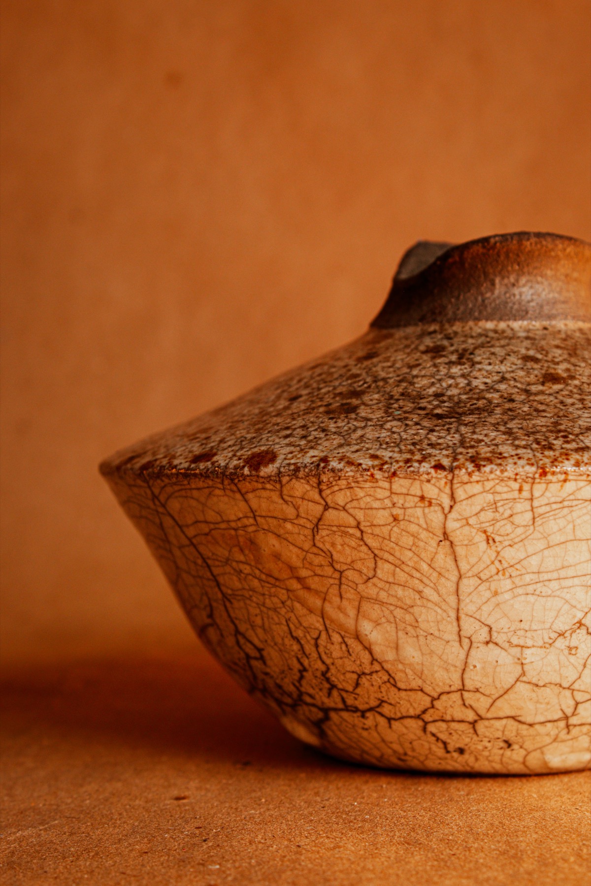 Detalhe de peça cerâmica raku com craquelado e tons quentes